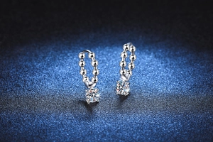 Macro shot of silver moissanite hoop earrings with brilliant-cut stones on dark background
