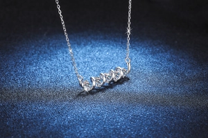 Detail of s925 silver necklace featuring five brilliant moissanite stones on a blue background