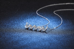 Macro detail of a 1.5ct moissanite necklace with a silver spiral pendant on blue surface