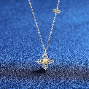 Vue macro du pendentif trèfle en moissanite 1,2 carat sur chaîne dorée fond bleu pailleté