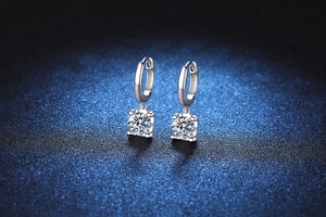 Close-up of S925 sterling silver moissanite earrings with four-prong settings on blue background