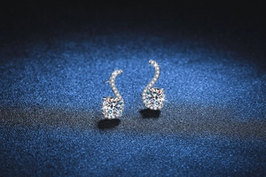 Detail of S-shaped sterling silver earrings with round moissanite on dark background