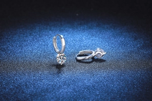 Detailed view of silver hoop earrings featuring a round moissanite solitaire drop pendant