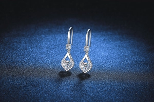 Detailed macro shot of pear-shaped sterling silver drop earrings with shimmering moissanite