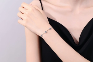Detail eines s925 Silberarmbands mit blauen Moissanit-Steinen am Handgelenk einer Frau