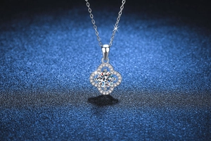 Macro shot of S925 silver four-leaf clover pendant with 1ct moissanite on blue background