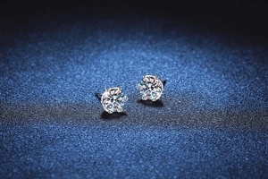 Macro shot of six-prong moissanite earrings in S925 sterling silver on blue background