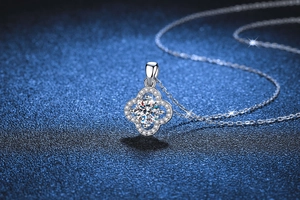 Close-up of S925 silver necklace with four-leaf clover moissanite pendant on blue background