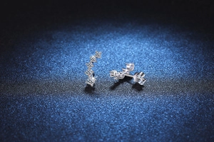 Macro shot of silver curved row earrings with five sparkling stones and butterfly back