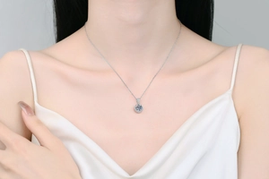 Close-up of a s925 silver necklace with 1 carat moissanite round pendant on model