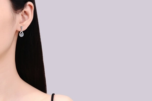 Detail view of pear-shaped 925 silver drop earrings with halo moissanite on a model