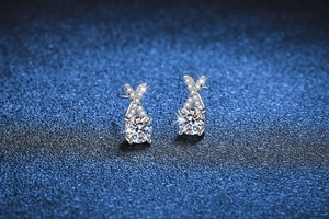 Macro shot of S925 silver X-shaped earrings with round moissanite in elegant blue setting