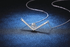 Macro detail of V-shaped 925 silver pendant necklace with sparkling 1ct moissanite diamond