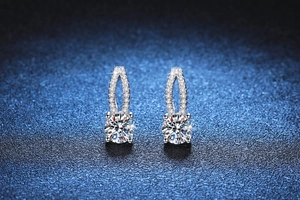 Close-up of asymmetric hollow silver earrings with 1 carat moissanite and micro zircons