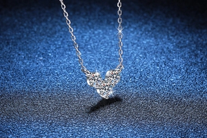 Vue macro d'un collier coeur en argent avec trois pierres moissanite et une chaine fine