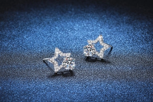 Macro detail of star-shaped S925 silver stud earrings with moissanite on starry background