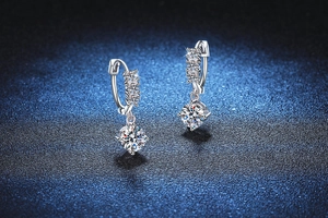 Close-up of S925 sterling silver drop earrings with 1ct Moissanite diamonds on blue surface