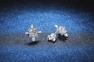 Dettaglio orecchini a fiocco di neve in argento S925 con pietre moissanite su sfondo blu