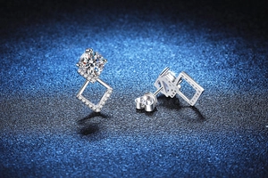 Dettaglio macro di orecchini geometrici in argento con moissanite da 1ct su sfondo stellato
