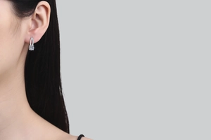 Close-up of sparkling round moissanite stud earring on ear with pave-set diamond details