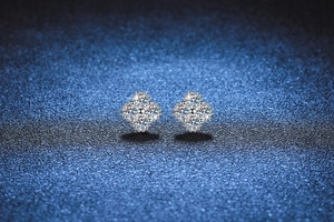 Close-up of S925 sterling silver four-leaf clover moissanite stud earrings on blue background