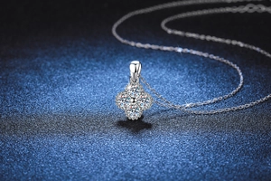 Macro shot of silver clover pendant with central moissanite and four small side stones