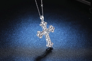 Macro detail of silver cross pendant with vintage scrollwork and sparkling moissanite gems