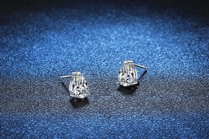 Macro detail of pear-cut moissanite earrings with 925 silver three-prong setting