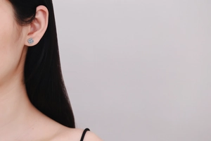 Detailed view of silver s925 clover stud earrings with pavé moissanite on model's ear