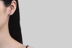 Detail view of pear-cut moissanite stud earring in 925 sterling silver on woman's ear