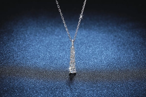 Macro shot of silver pendant with five graduated moissanite stones on thin cable chain