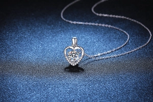 Gros plan du pendentif cœur en argent S925 avec moissanite de 1ct sur fond bleu foncé