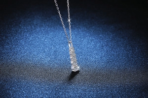 Detailed view of silver necklace with five graduated round moissanite stones in bar pendant