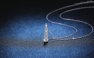 Detail view of graduated moissanite pendant necklace on sparkling blue background