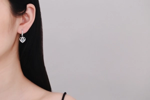 Close-up of S925 silver heart earrings with blue moissanite on a model's ear
