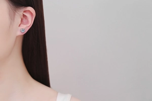 Close-up of classic six-prong moissanite stud earring on ear with silver finish