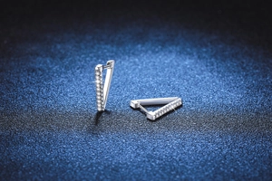 Close-up of geometric V-shaped 925 silver earrings with sparkling pavé moissanite stones