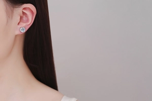 Close-up of classic S925 silver moissanite halo stud earring on a female ear model