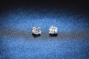 Macro de boucles d'oreilles moissanite à 4 griffes et base argentée sur fond bleu