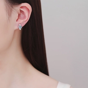 Elegant S925 sterling silver four-prong moissanite stud earrings worn by a female model