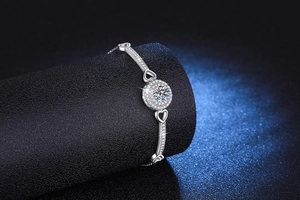 Macro detail of 925 silver bracelet with sparkling moissanite heart and round pendant