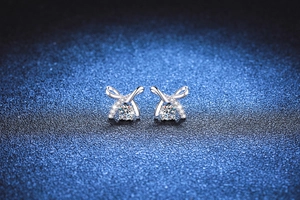 Macro detail of 925 silver cross ribbon earrings featuring Moissanite center stone