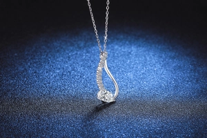 Macro detail of S925 silver pear-cut moissanite pendant with pavé diamond accents