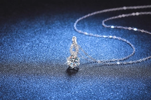 Close-up of S925 sterling silver gourd necklace with 1 carat moissanite on blue background
