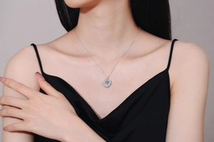 Detail of a 2-carat heart-shaped moissanite pendant on a silver necklace worn by a model