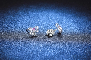 Detailed view of S925 silver bow stud earrings with pink and clear moissanite stones