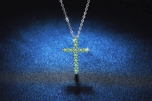 Detail of silver S925 cross pendant featuring pavé set green moissanite crystals