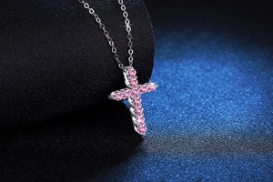 Macro shot of a silver S925 cross pendant featuring sparkling round-cut pink moissanite stones