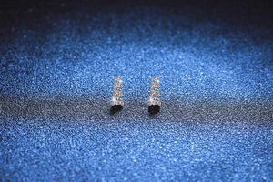 Detail of rose gold stud earrings featuring three vertically stacked brilliant round stones