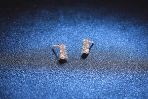 Macro detail of rose gold 925 sterling silver stud earrings with three round moissanite stones